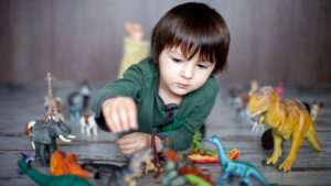 bambino che gioca a terra con dinosauri giocattolo